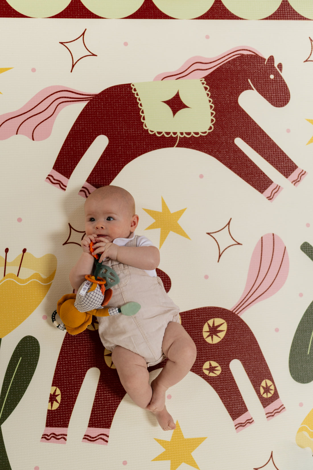 Little baby on a playmat with horse print
