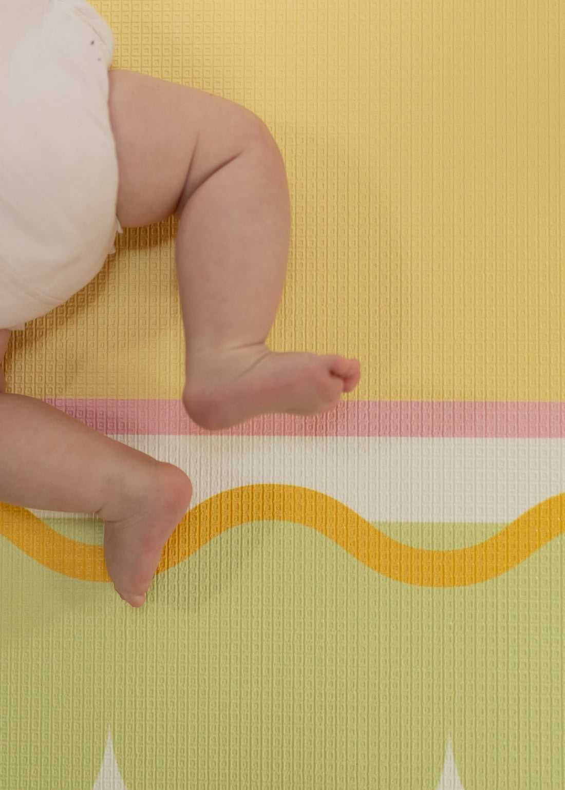 Texture details Baby legs on a colorful play mat with geometric patterns