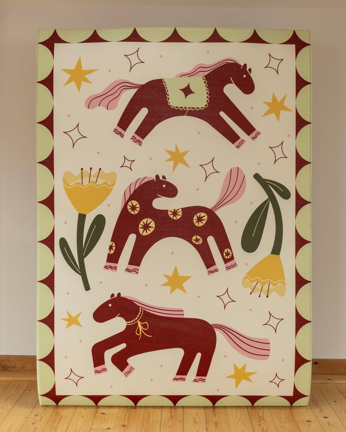 The artwork with horse designs on the play mat on a plain wall.
